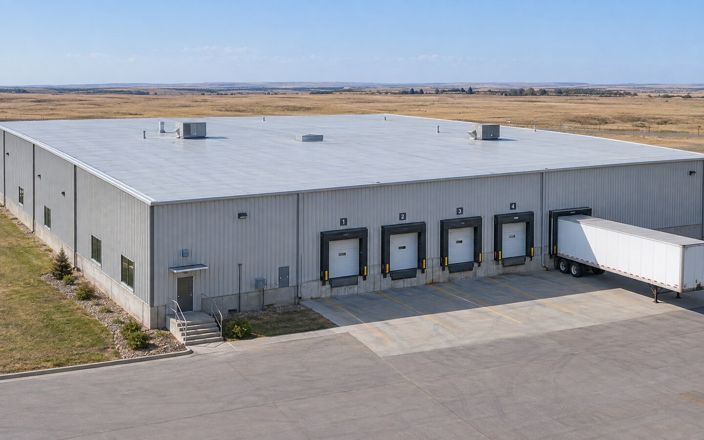 Illustrative industrial warehouse with a broad low-slope membrane roof and loading docks