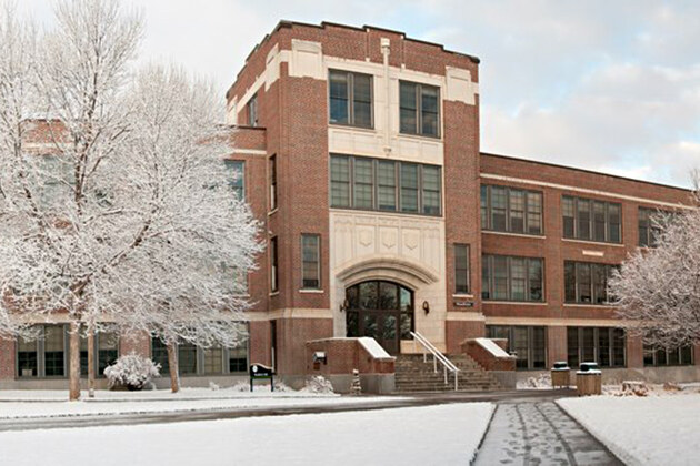 Brick building with a central entrance and snow-covered grounds from Lowe Roofing's project gallery